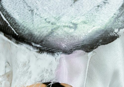 Detailed macro shot of fabric being sanded in a workshop setting.
