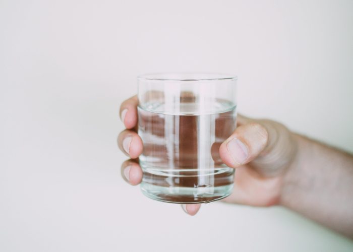 A close-up shot of a hand holding a clear glass of water, symbolizing refreshment.